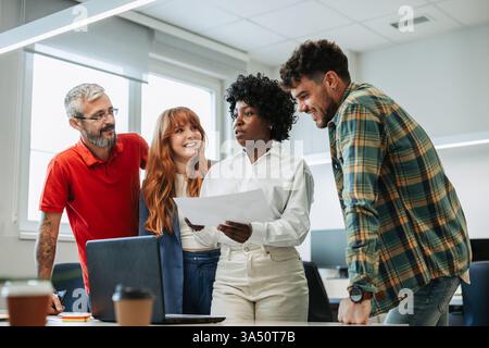 Donna d'affari nera con capelli ricci tiene un documento mentre fa brainstorming con colleghi caucasici intorno a un tavolo. Un team multirazziale collabora in un ambiente di lavoro moderno. Ideale per gli argomenti relativi al lavoro di squadra, al brainstorming e alla collaborazione in ufficio. Foto Stock