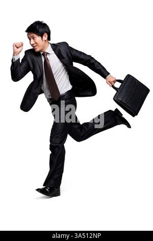 Ripresa completa di un uomo d'affari cinese che corre, trasuda energia e determinazione. Un'immagine dinamica dello stile di vita aziendale adatta a campagne di business, leadership e produttività. Ideale per articoli sul traffico e sui professionisti in movimento. Foto Stock