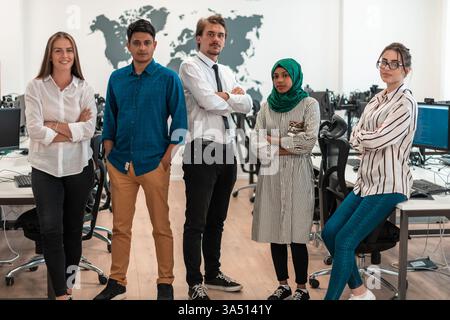 Ritratto di un giovane ed eccitato team aziendale multietnico composto da sviluppatori di software in piedi e che guarda la fotocamera nel moderno ufficio di startup. Alta qualità Foto Stock