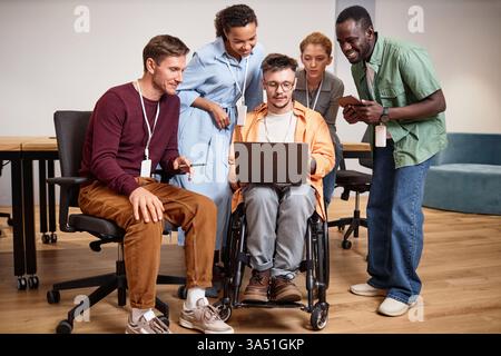 Gruppo eterogeneo di professionisti che collaborano a una presentazione online. Lavorano insieme in un ufficio moderno con computer portatili e schermi digitali. Ideale per comunicazioni aziendali, lavoro di squadra, lavoro in remoto e campagne aziendali. Foto Stock