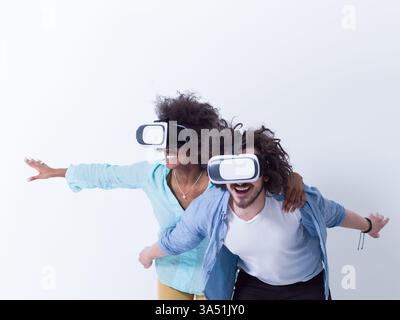 Coppia felice che esplora la realtà virtuale indossando occhiali VR su uno sfondo bianco e pulito. Un'immagine tecnologica contemporanea adatta all'innovazione digitale, ai videogame e al futuro della videografica tecnologica. Foto Stock