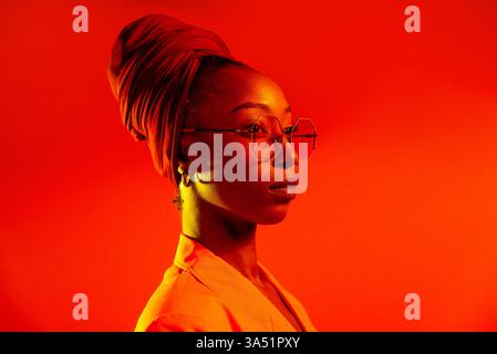 Bella donna afroamericana con pigtail afro che indossa abiti eleganti per un ritratto in studio. Immagini di moda vivaci adatte a campagne di bellezza, stile di vita e empowerment. Una rappresentazione moderna e inclusiva dello stile giovanile. Foto Stock