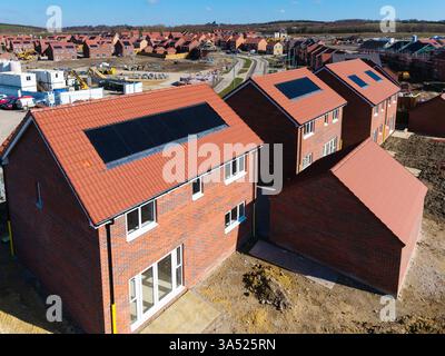 I tetti di una fila di case di nuova costruzione in un cantiere con tetto integrato o pannelli solari integrati nel tetto per un'energia economica e sostenibile in un ambiente ecologico Foto Stock