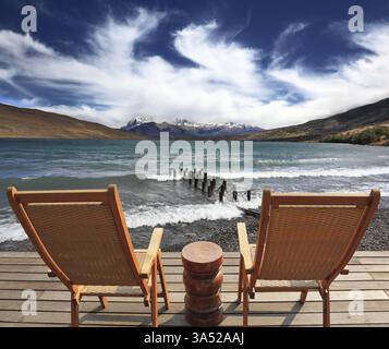 Il luogo confortevole per godersi la bellezza del lago e delle nuvole in Patagonia. Due sedie di legno pieghevoli e un piccolo comodino sul lungomare Foto Stock