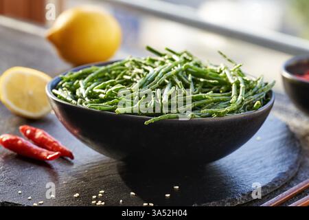 Alghe verdi fresche di Salicornia in un recipiente con limone, peperoncino e semi di sesamo Foto Stock