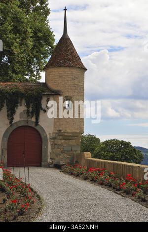 Il castello medievale dell'alta Savoia. Torre rotonda angolare, parte delle pareti protettive e massiccio cancello rosso in legno Foto Stock