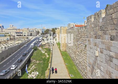 Cammina lungo le mura dell'antica Gerusalemme. Vista della nuova Gerusalemme - l'autostrada con automobili, edifici moderni e persone che camminano Foto Stock