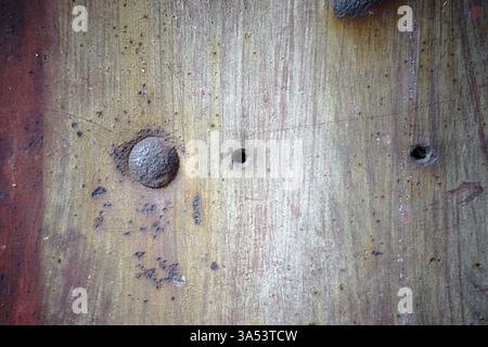 Primo piano di una superficie metallica arrugginita con bolle di ruggine e rivetti arrugginiti Foto Stock