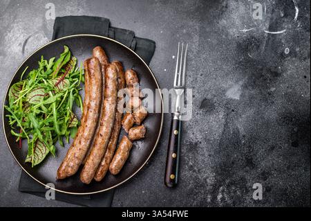 Salsiccia grigliata affumicata con grigliate, perfetta per soddisfare le voglie al barbecue e per eventi informali. sfondo nero. vista dall'alto. Foto Stock