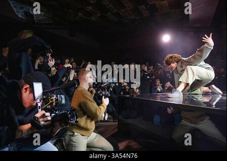 Kiev, Ucraina - 17 febbraio 2025. Durante la sfilata di moda Gasanova, le modelle ballano con sicurezza lungo la passerella, mostrando design unici. Gli spettatori catturano i momenti sul telefono. Foto Stock