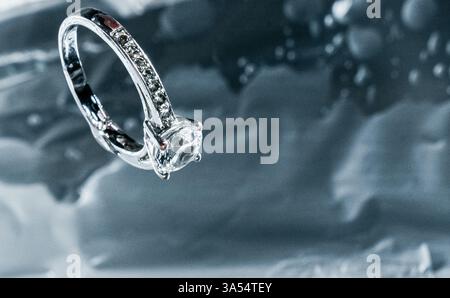 Primo piano di un elegante anello di innesto diamantato appoggiato su una superficie riflettente. L'immagine evidenzia i dettagli scintillanti dell'anello e del suo Foto Stock
