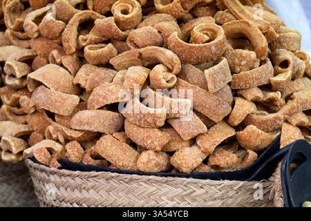 Primo piano di un mucchio di pancia di maiale fritta croccante impilata in un cestino di vimini. La texture dorata e croccante mette in risalto la saporita preparazione di questa classe Foto Stock