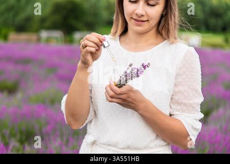 Donna nel campo della lavanda che tiene in mano olio essenziale Foto Stock