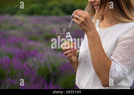 Donna nel campo della lavanda che tiene in mano olio essenziale Foto Stock