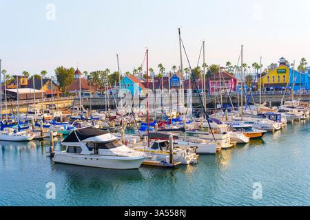 Long Beach, California - 11 gennaio 2025: Barche colorate attraccate nelle calme acque di Rainbow Harbor, circondate da vivaci edifici del litorale Foto Stock