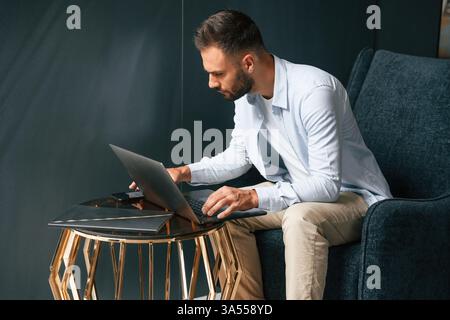 Concentrato, sicuro di sé. L'uomo d'affari è seduto e lavora utilizzando un computer portatile. Foto Stock