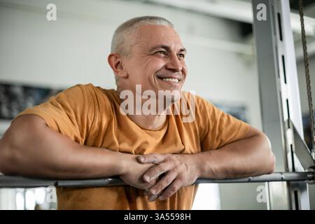 Uomo sorridente che riposa dopo un allenamento in palestra Foto Stock