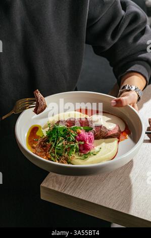 piatto in mano. medaglioni di manzo con purè di patate e sugo di carne Foto Stock