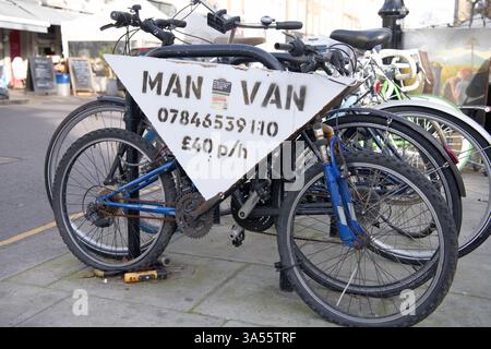 Uomo e un cartello pubblicitario Van su una bicicletta incatenata ad altre biciclette a Notting Hill, Londra Foto Stock