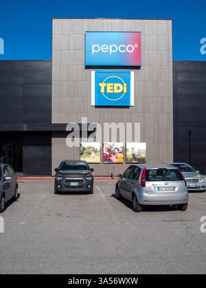 Moderno centro commerciale con loghi Pepco e Tedi sulla facciata e auto parcheggiate in primo piano in una giornata di sole Foto Stock