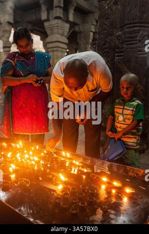 Famiglia indiana padre madre figlio che adorano illuminando lampade ghee nel tempio indù tempe Sri Ranganathaswamy Foto Stock