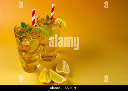 Due bicchieri di tè ghiacciato con fette di lime e limone. La bevanda è servita in un bicchiere con foglie di menta sulla parte superiore e cannucce bianche e rosse. Foto Stock