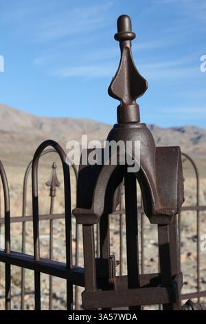 Una finitura decorativa sopra un palo d'angolo di una recinzione intorno a una tomba nel deserto. Foto Stock