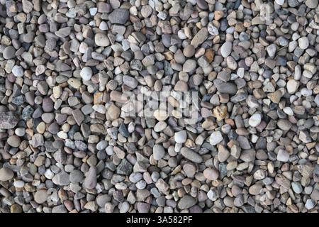 Una pila di rocce con una varietà di dimensioni e colori. Le rocce sono sparse su tutto il terreno, creando una superficie ruvida e irregolare. Concetto di rugge Foto Stock