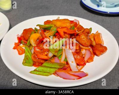 maiale dolce e aspro strapazzato con peperoni rossi verdi sul piatto bianco pronto per essere mangiato Foto Stock