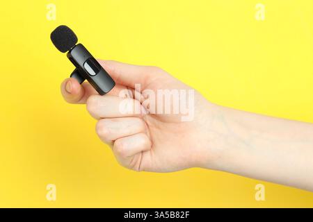 Donna con microfono lavalier su sfondo giallo, primo piano Foto Stock