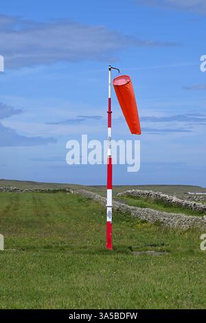Calza a vento rossa su palo a strisce rosse e bianche presso l'aeroporto di Papa Westray alle Orcadi Foto Stock