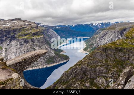 Vista mozzafiato di un profondo fiordo norvegese circondato dalle maestose montagne sotto un suggestivo cielo nuvoloso catturato in questo paesaggio mozzafiato Foto Stock