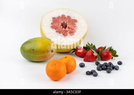 la composizione ravvicinata di mandarini e pamela si trova su sfondo bianco e fragole mirtilli e manghi rispettosi dell'ambiente Foto Stock