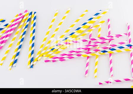 foto in alto su sfondo bianco ci sono molte provette colorate a strisce di carta per cocktail e bevande diverse, tubi a strisce rosa gialle e blu primavera Foto Stock