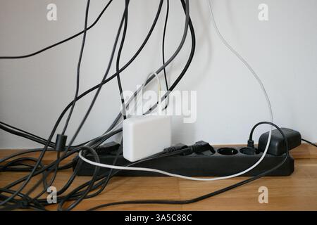 Molti fili in una presa sul posto di lavoro. Caos nel cablaggio. Concetto del problema del risparmio di spazio e dell'estetica. Foto Stock