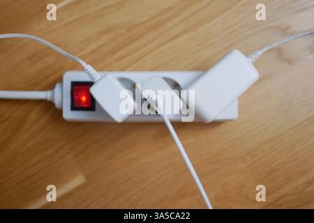 Tre cavi elettrici sono collegati a una prolunga presa multipla. Foto Stock