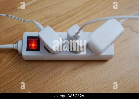 Tre cavi elettrici sono collegati a una prolunga presa multipla. Foto Stock