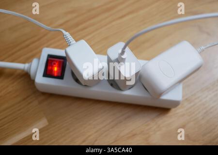 Tre cavi elettrici sono collegati a una prolunga presa multipla. Foto Stock