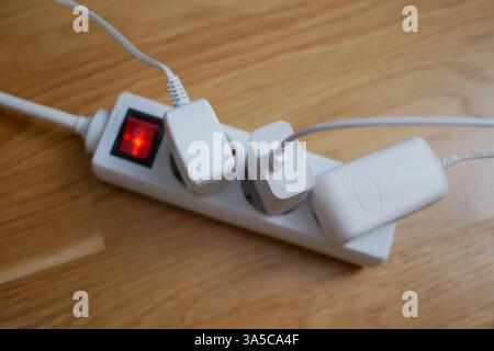 Tre cavi elettrici sono collegati a una prolunga presa multipla. Foto Stock