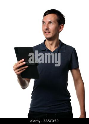Un uomo professionista che regge un tablet in una posa elegante e coinvolgente che trasuda fiducia Foto Stock