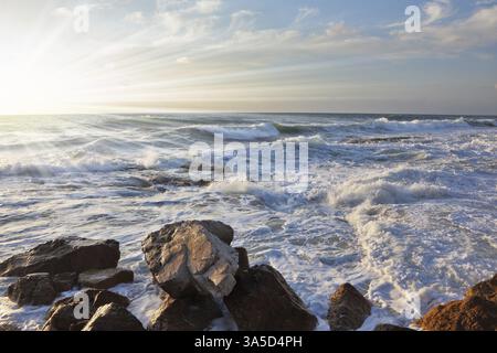 Magnifico tramonto sul Mar Mediterraneo. Le onde di tempesta si infrangono sulle pietre di frangiflutti sulla banchina. Tel Aviv, primavera Foto Stock