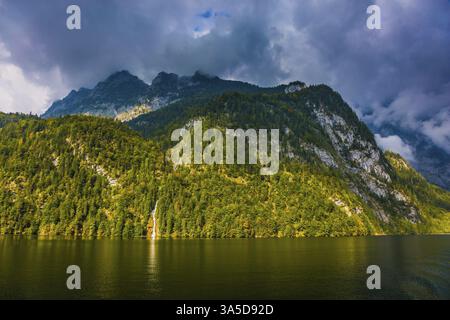 Pittoresche cascate della foresta e ripide rive del lago. Koenigssee - il lago più pulito della Baviera, Germania. Il lago è circondato da montagne. T Foto Stock