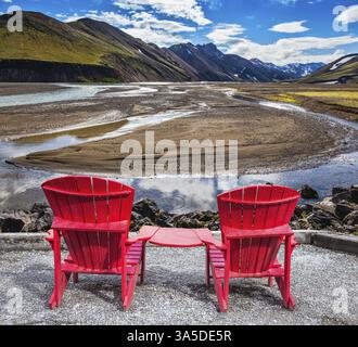 Montagne multicolore di riolite minerale sono illuminate dal sole. Due chaise longue rosse sono ideali per i turisti Foto Stock
