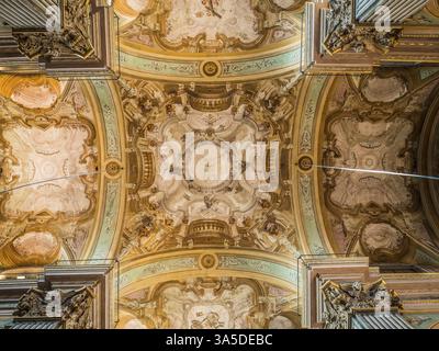 Da sotto l'incredibile soffitto ornamentale e le colonne all'interno dell'antico palazzo barocco in Italia Foto Stock