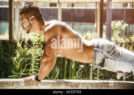 Vista laterale di uomo bello fare push-up all'aperto Foto Stock