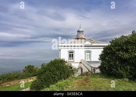 Faro bianco di neve sulla scogliera. CANDAS. Costa atlantica, Spagna. Viaggio romantico in Spagna. Clima autunnale mite. Parte della famosa spiaggia della Costa Verde Foto Stock