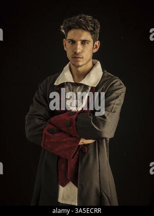 Giovane e sicuro modello ispanico, vestito con elegante abito vintage, che guarda la fotocamera su sfondo nero Foto Stock