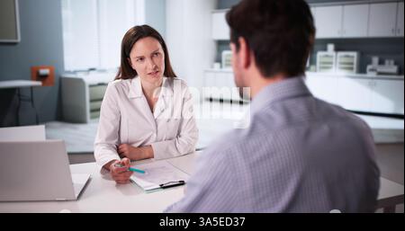 Consultazione tra il medico maschile e la paziente femminile in ambiente ospedaliero. Foto Stock