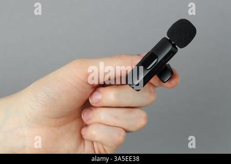 Donna con microfono lavalier su sfondo grigio chiaro, primo piano Foto Stock