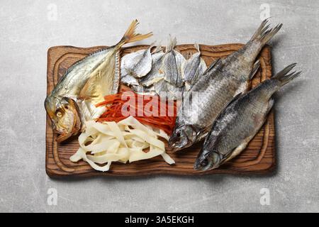 Molti diversi spuntini di pesce secco sul tavolo grigio chiaro, vista dall'alto Foto Stock